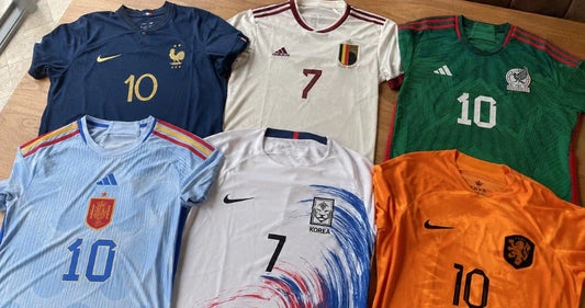 Six maillots de football de sélections nationales posés à plat sur une table en bois, avec France, Belgique, Mexique, Espagne, Corée du Sud et Pays-Bas.