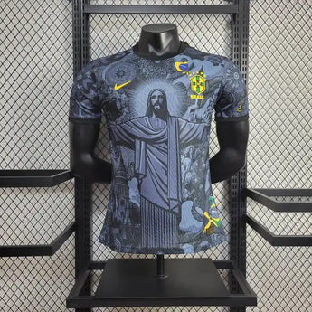 Maillot de l'équipe nationale du Brésil présentant une œuvre de Christ le Rédempteur dans des tons gris et bleus avec des accents jaunes.